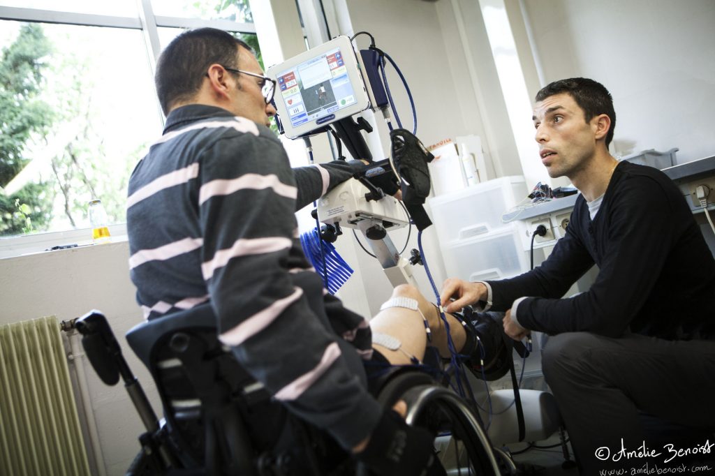 Sébastien aide Julien, paraplégique et membre de l’équipe de l’ENS pour le Cybathlon, à positionner les électrodes et à régler l'intensité de l'entrainement.